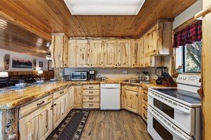 A kitchen with wooden cabinets, a microwave, a dishwasher, and a stove. - Centennial Chalet , Tranquil cabin 20 min from Yellowstone (Island Park)