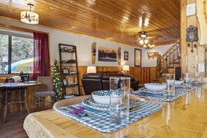 A wooden interior with a dining table set for two, a Christmas tree, and various wall decorations. - Centennial Chalet , Tranquil cabin 20 min from Yellowstone (Island Park)