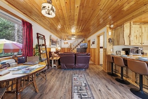 A cozy cabin interior with a wooden ceiling, a sofa, a dining table, and a kitchen area. - Centennial Chalet , Tranquil cabin 20 min from Yellowstone (Island Park)