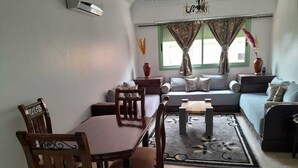 A living room with a dining table, chairs, a sofa, and a coffee table. - Apartment Gueliz - Near ONCF station - Marrakech (Marrakech)