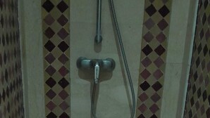 A shower area with a tiled wall, a showerhead, and a drain. - Apartment Gueliz - Near ONCF station - Marrakech (Marrakech)