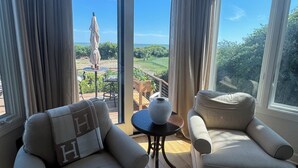 Una habitación con dos sofás, una mesita y vistas a un jardín y al cielo a través de amplios ventanales.