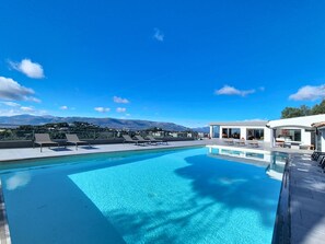 A rooftop pool with clear blue water, surrounded by lounge chairs and a modern building with large windows. - Domaine Datcha - La Dolce Vita, in complete privacy (Aspremont)