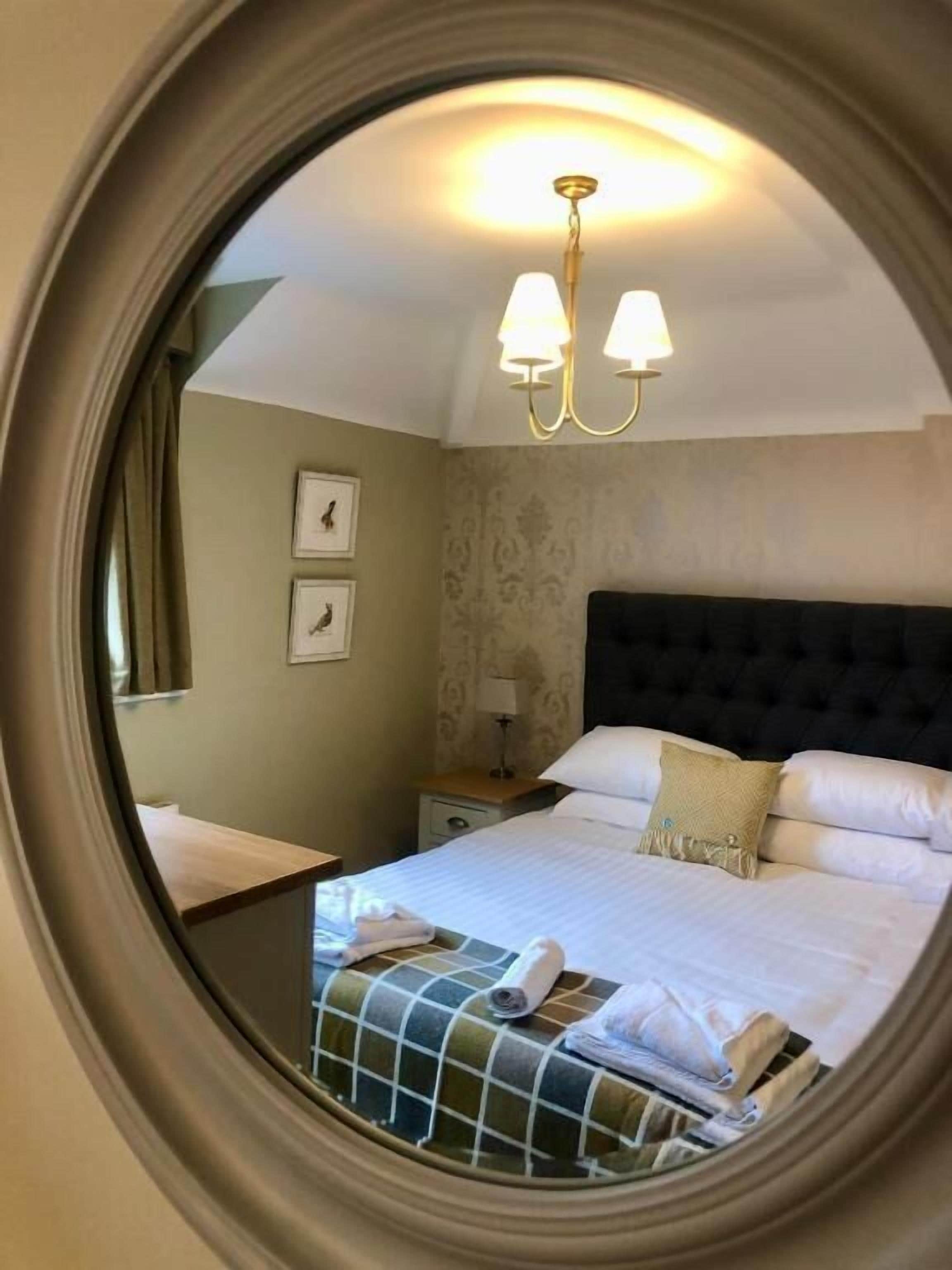 A hotel room with a bed, a nightstand, a lamp, and a wall-mounted picture.