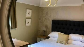 A hotel room with a bed, a nightstand, a lamp, and a wall-mounted picture.