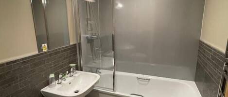 Ein modernes Badezimmer mit einer gläsernen Duschkabine, einer weißen Badewanne, einem Waschbecken mit Spiegel und einer Toilette.
