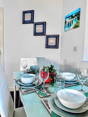 A dining area with a table set for four, featuring blue and white plates, glasses, and a decorative centerpiece. - Contractor-friendly 2BR Gem Wi-fi & Free Parking (Warrington)