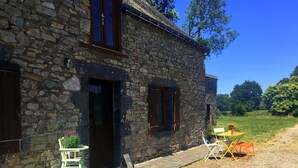 A stone building with a door and windows, a small outdoor seating area with a table and chairs, and a grassy area in the background. - Delightful 2-bedroom cottage perfect for a revitalizing retreat in Brittany (Ruffiac)