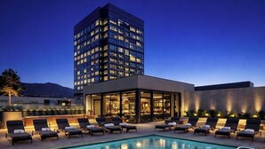 Piscina com espreguiçadeiras e um edifício moderno ao fundo.