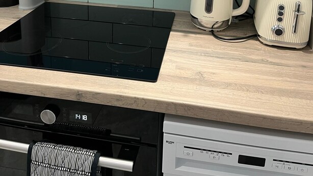 A kitchen with a black induction cooktop, a coffee maker, and a toaster on the counter. - Agape Hub Holiday Home (Nottingham)