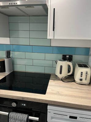 A kitchen with a black induction cooktop, a coffee maker, and a toaster on the counter. - Agape Hub Holiday Home (Nottingham)