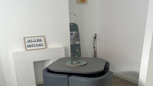 A dining area with a round table, four chairs, a green floral rug, and a sign on the wall. - Agape Hub Holiday Home (Nottingham)