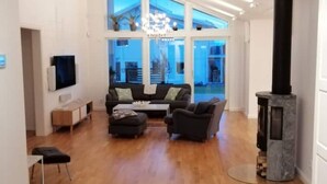Un amplio salón con chimenea, un conjunto de sofás y un televisor.