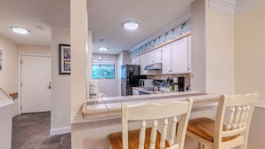 A kitchen with white cabinets, a countertop, and two wooden chairs. - 2BR Lagoon View Villa - Walk to Coligny (Hilton Head Island)