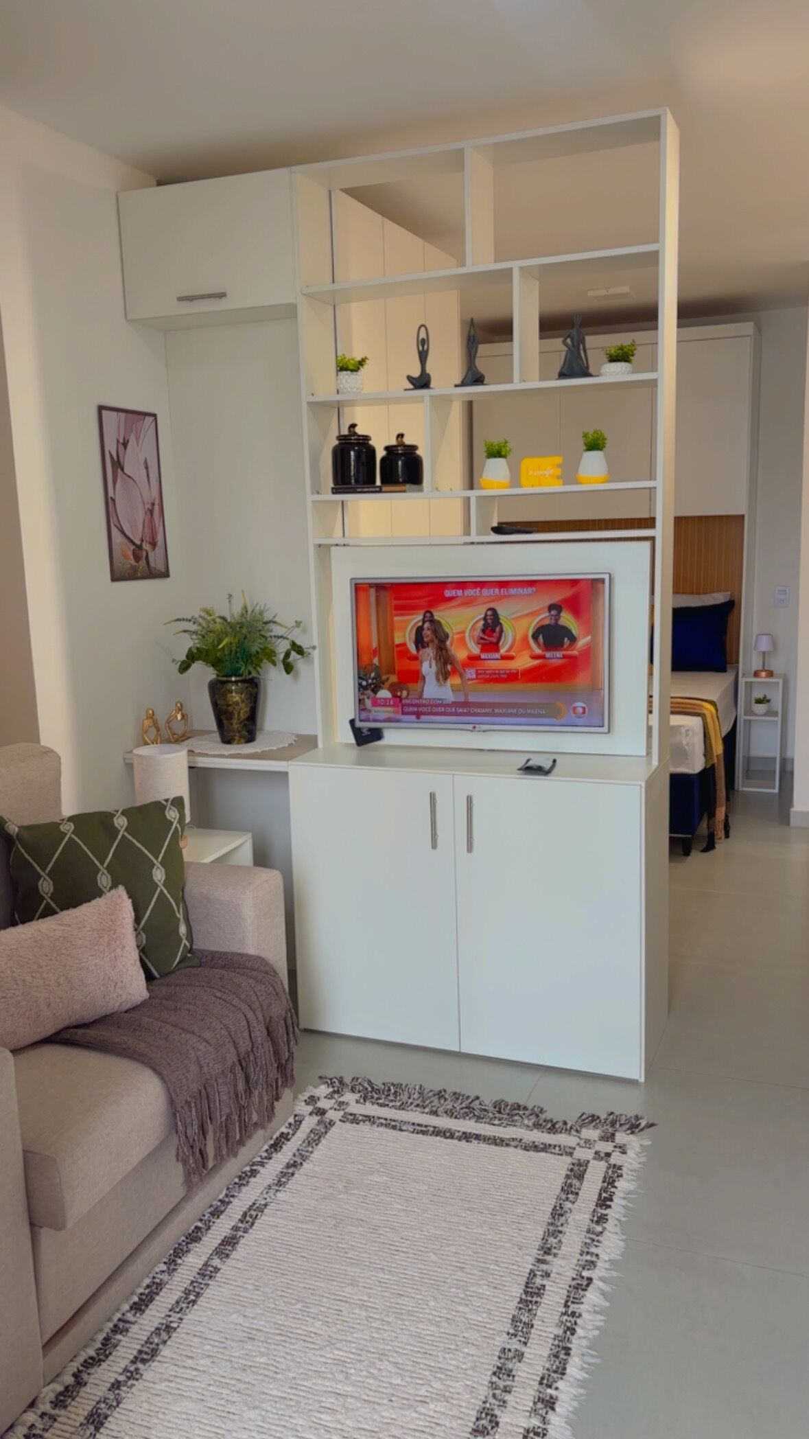 Een woonkamer met een witte tv-kast, een bank, een salontafel en een televisie.