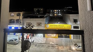 Udsigt fra et vindue over en gade om natten med bygninger i baggrunden.