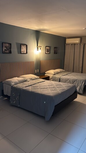 A hotel room with two beds, a wall-mounted air conditioner, and a light fixture. - hotel once11 (Monterrey)
