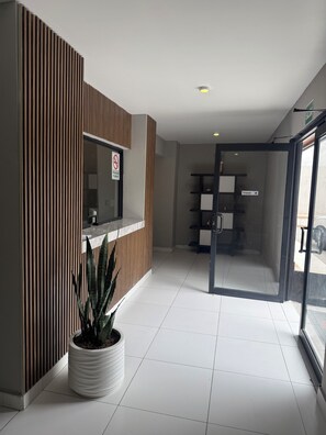 A reception area with a wooden panel wall, a potted plant, a no-smoking sign, and a glass door leading to a room. - hotel once11 (Monterrey)
