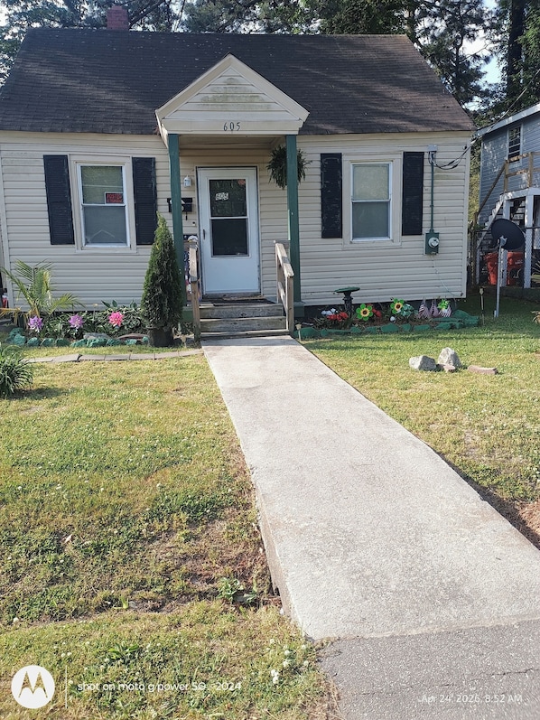 A single-story house with a front porch, a number '605' on the door, and a small front yard with a pathway leading to the entrance.