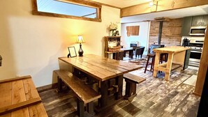 Ein gemütliches, rustikales Interieur mit einem Holzespeisetisch, Bänken und einer Küchenzeile mit modernen Geräten.