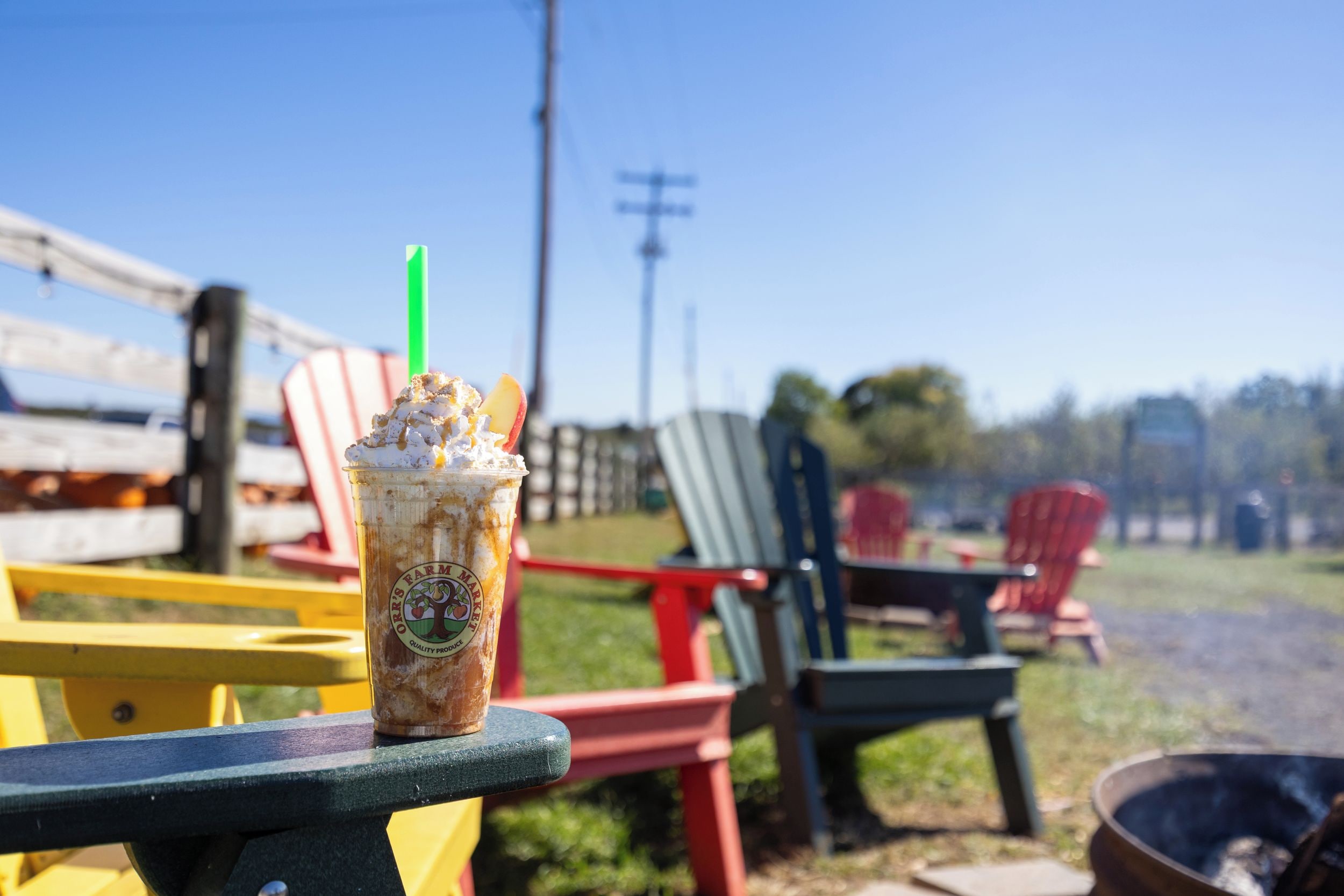 A beverage in a branded cup on a park bench with colorful chairs in the background.