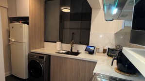 Una cocina compacta con lavadora integrada, una estufa moderna y un lavamanos pequeño.