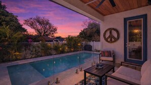 Zona de piscina con vista al atardecer, ventilador de techo y una decoración con el símbolo de la paz.