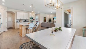 Una cocina amplia con una isla grande, modernos apliques colgantes y vistas a la ciudad.