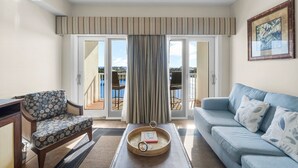 Ein Wohnzimmer mit einer Couch, einem Sessel, einem Couchtisch mit Tablett und Blick durch eine Schiebetür auf eine Terrassenanlage.