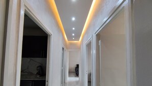 Un corridoio stretto con pareti bianche e un soffitto con faretti.