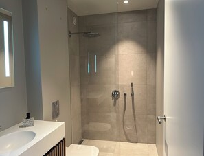 Un baño moderno con ducha, lavamanos e inodoro.