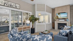 A living room with a large window, a television, a fireplace, and a sign that reads "Welcome to the PORCH". - Golf Cart - Pool - Walk to Beach - Fully Remodeled - Crystal Beach - Sleeps 10 (Destin)