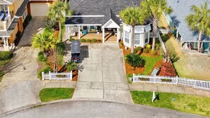 A residential area with multiple houses, a driveway, and a white picket fence. - Golf Cart - Pool - Walk to Beach - Fully Remodeled - Crystal Beach - Sleeps 10 (Destin)