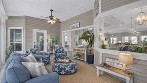 A spacious living room with a large sofa, star-patterned ottoman, and a bench with a sign. - Golf Cart - Pool - Walk to Beach - Fully Remodeled - Crystal Beach - Sleeps 10 (Destin)