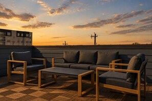 Eine Dachterrasse mit einer Sofagarnitur, Sesseln und einem Couchtisch.