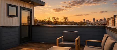 Une terrasse sur le toit offrant une vue panoramique sur la ville, avec un sol en bois et du mobilier d’extérieur.