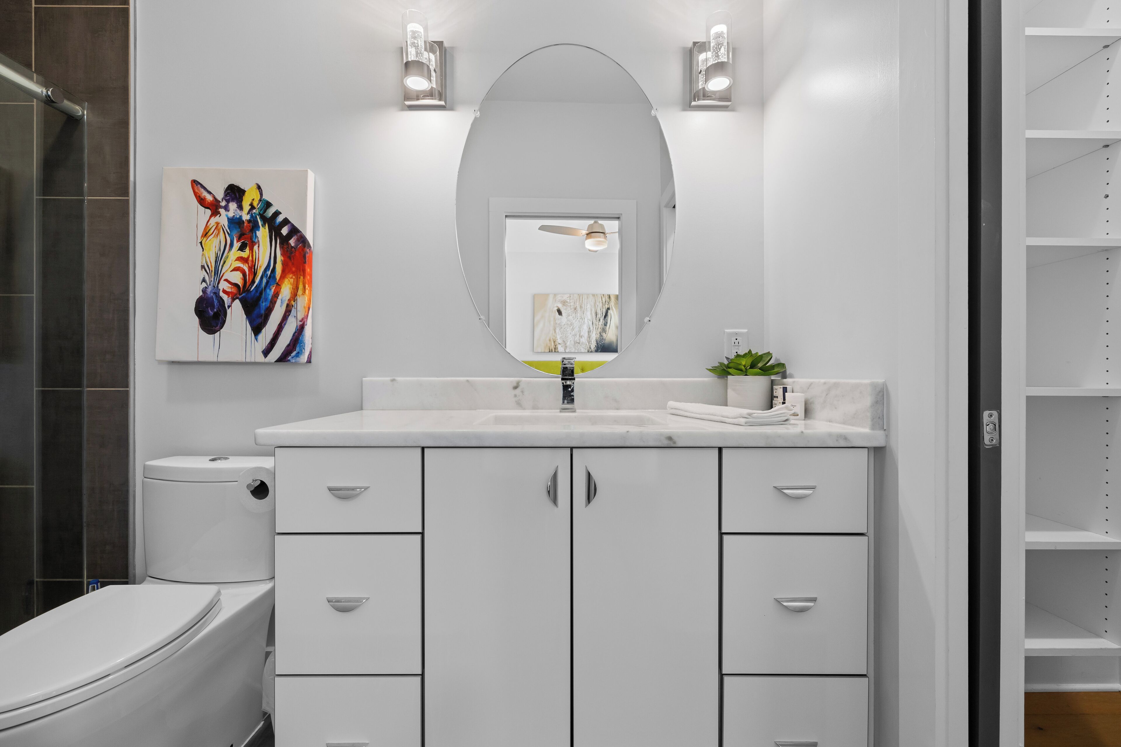 Bright bathroom vanity with colorful artwork and plenty of storage.