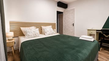 A neatly arranged hotel room with a bed, bedside table, lamp, and a desk with a chair.