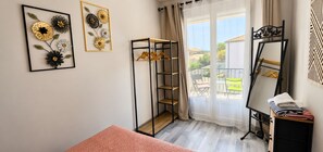 A room with a bed, a wardrobe, a mirror, and a window with a view of the outside. - Le Cocon des Romarins – 3 bedrooms, air conditioning, balcony, and shared pool (Montélimar)