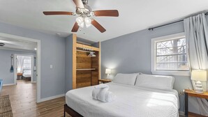 A bedroom with a bed, wooden wardrobe, ceiling fan, and a window with curtains. - Foley Riverfront Escape Kayaks Firepit Near Beach (Foley)