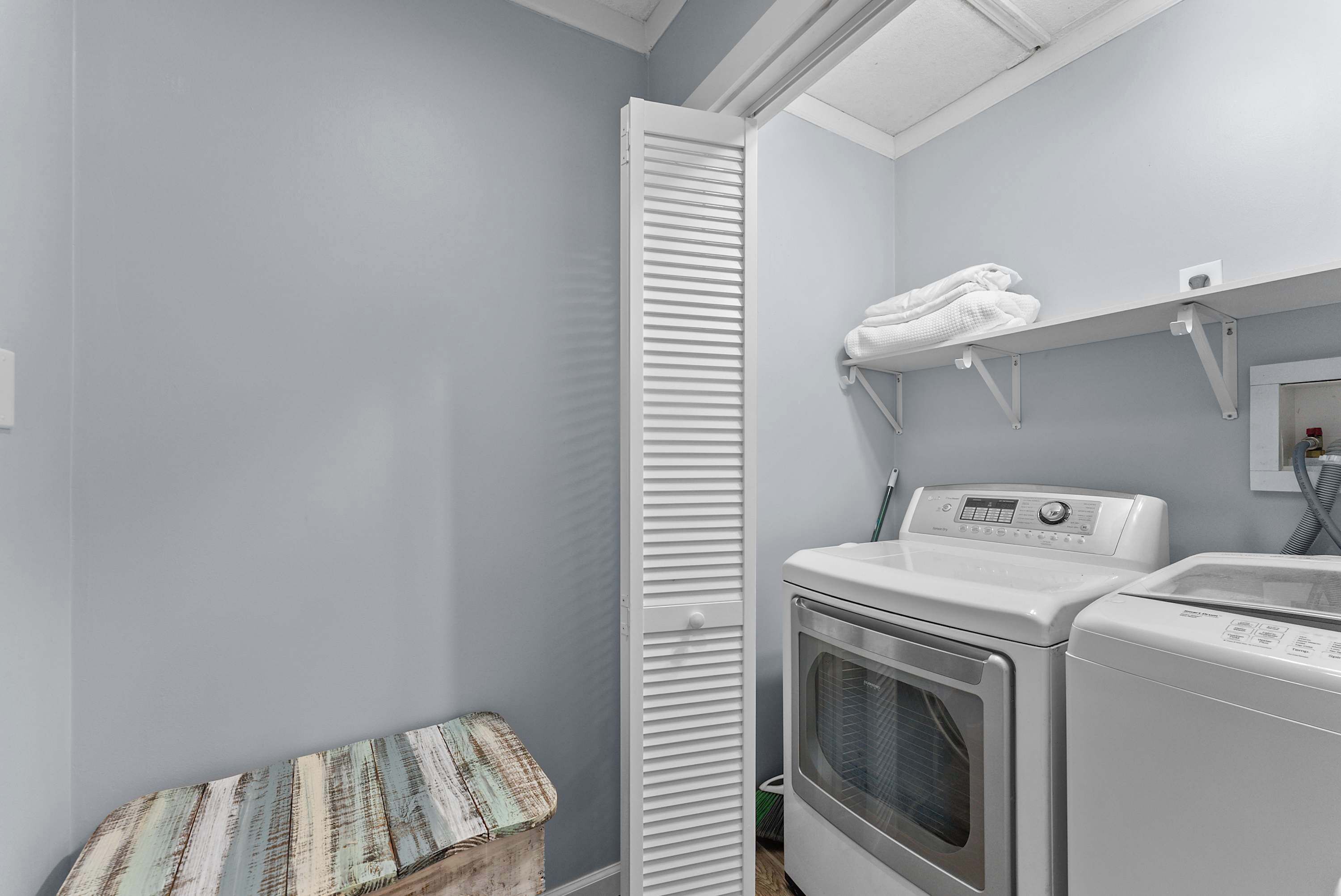 A laundry room with a washing machine, dryer, and a drying rack.