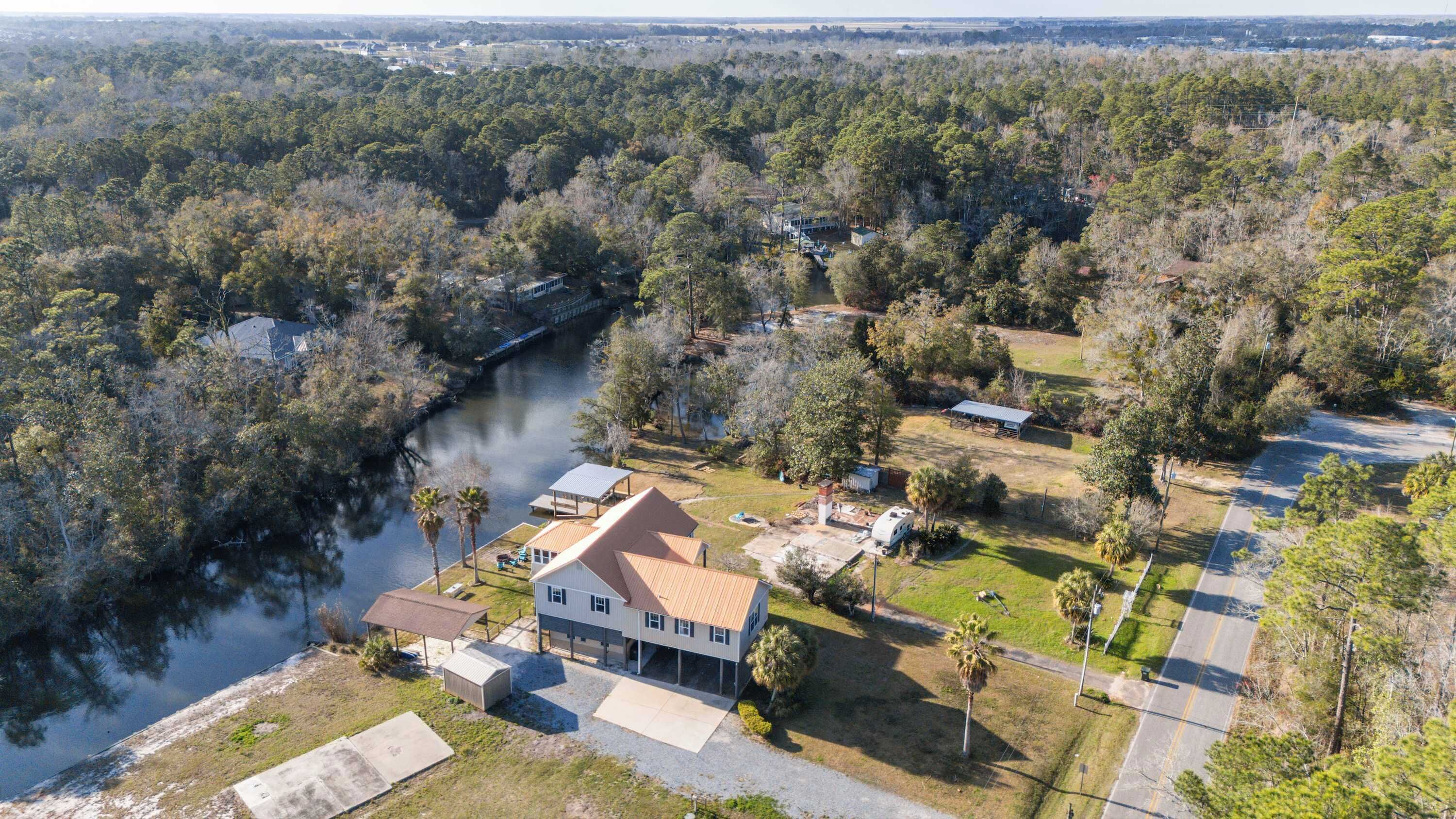 A large house with a covered porch, a small dock, and a river in the background.