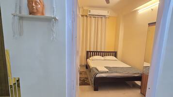 A bedroom with a bed, a ceiling fan, and a wall-mounted air conditioner.