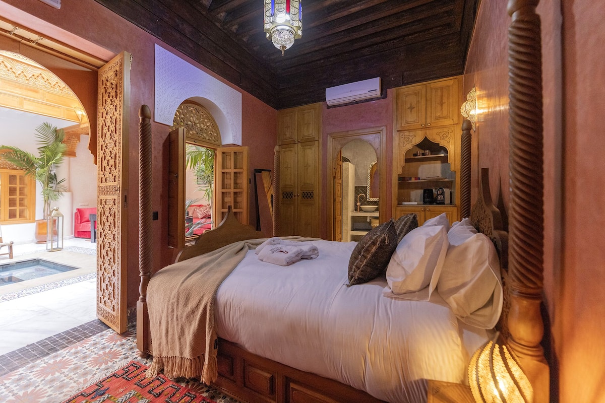 A bedroom with a bed, wooden headboard, arched doorways, and a ceiling fan.