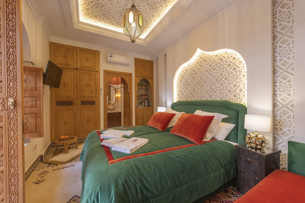 A room with a large bed, a television, wooden cabinets, and a patterned wall.