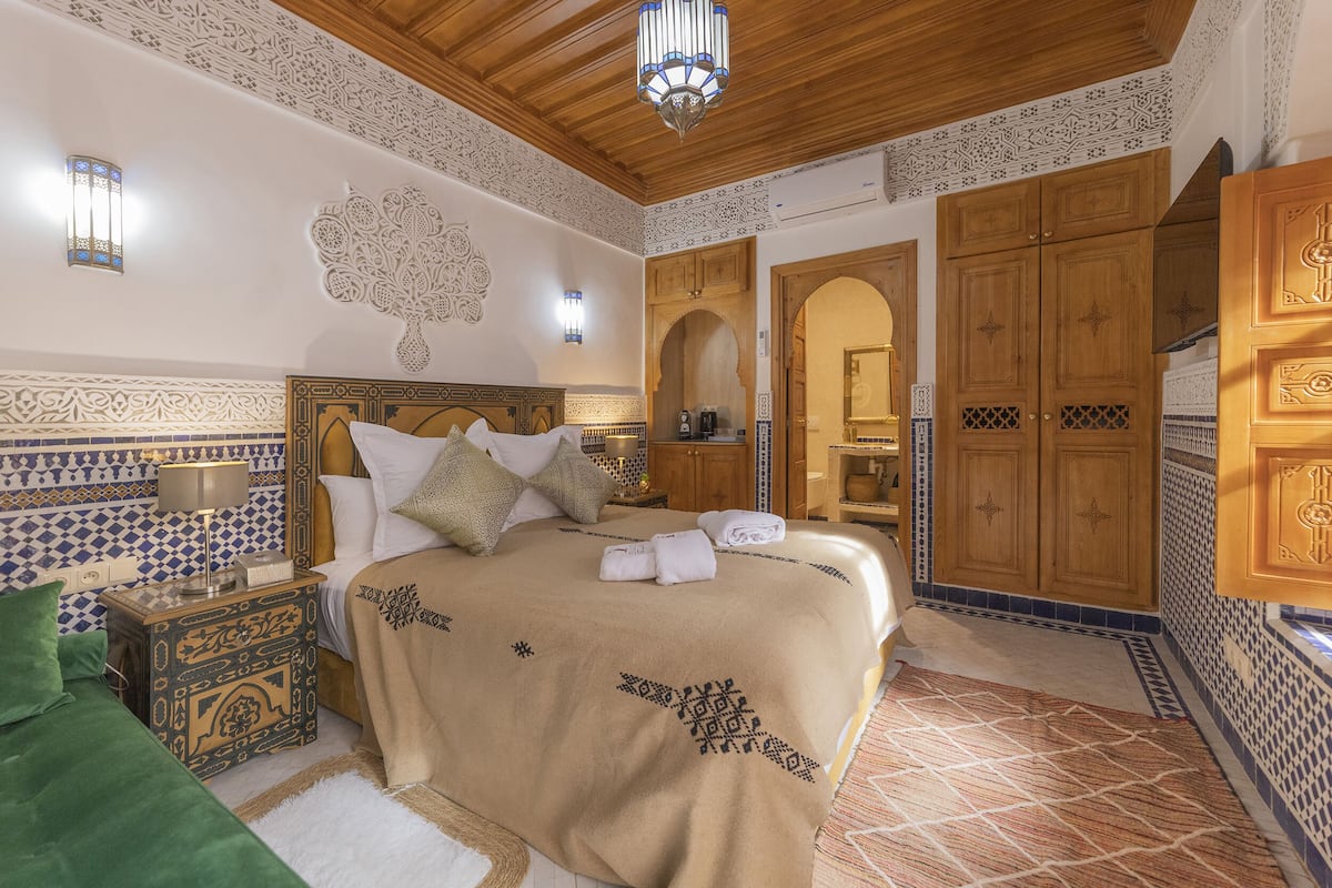 A bedroom with a bed, nightstand, and a wooden wardrobe.