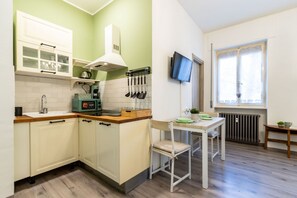 Una cucina compatta con forno a microonde, bollitore e utensili sul piano di lavoro.