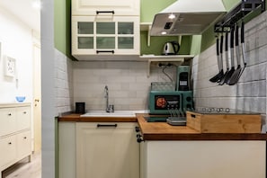 Una cocina con armarios blancos, encimera de madera, microondas y utensilios colgantes.
