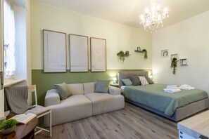 Un dormitorio moderno con sofá, cama, lámpara de araña y obras de arte en las paredes.