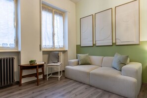 Una sala de estar con un sofá, una silla, una mesita y un radiador.